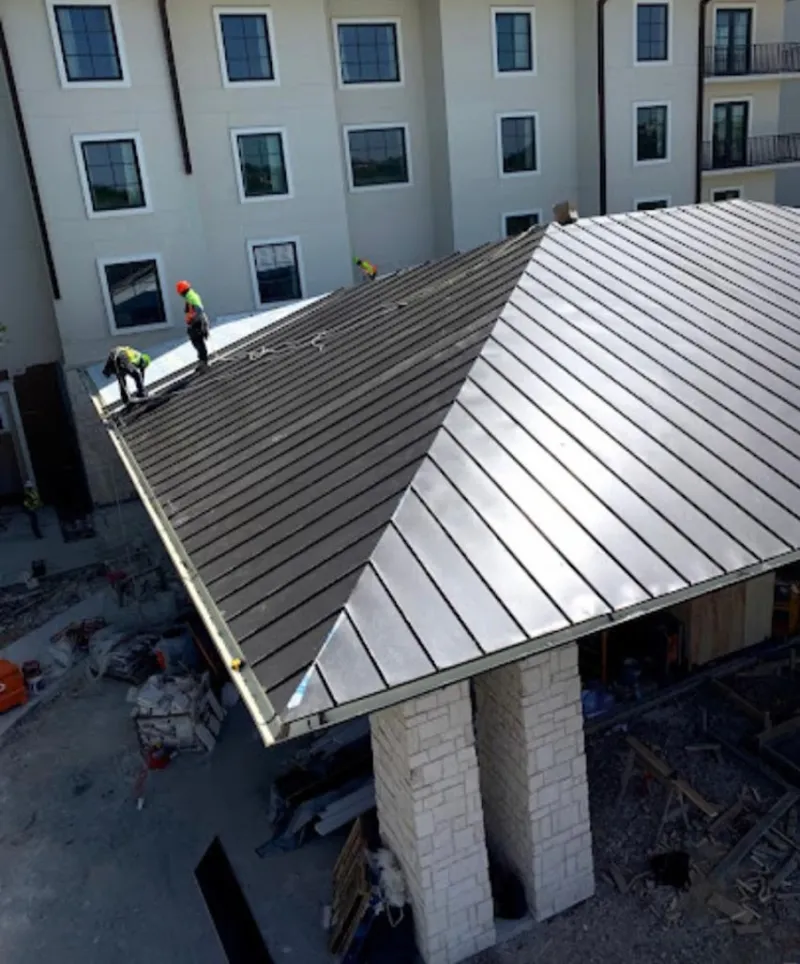Crew installing standing seam metal roof panels on a commercial project in Farmville